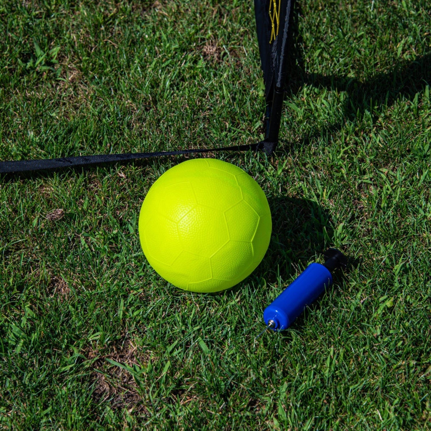 Yellow ball and blue pump on grass